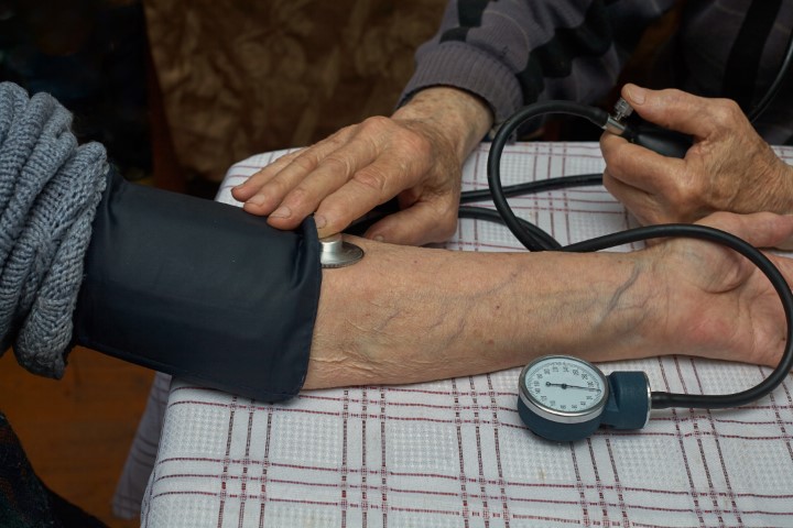 Measurement of blood pressure in the elderly with a manual blood pressure monitor. A tonometer and a phonendoscope are on hand. Horizontal frame.